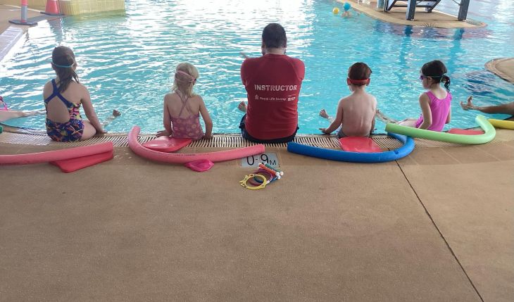 Learning water survival skills, a class of children poolside.